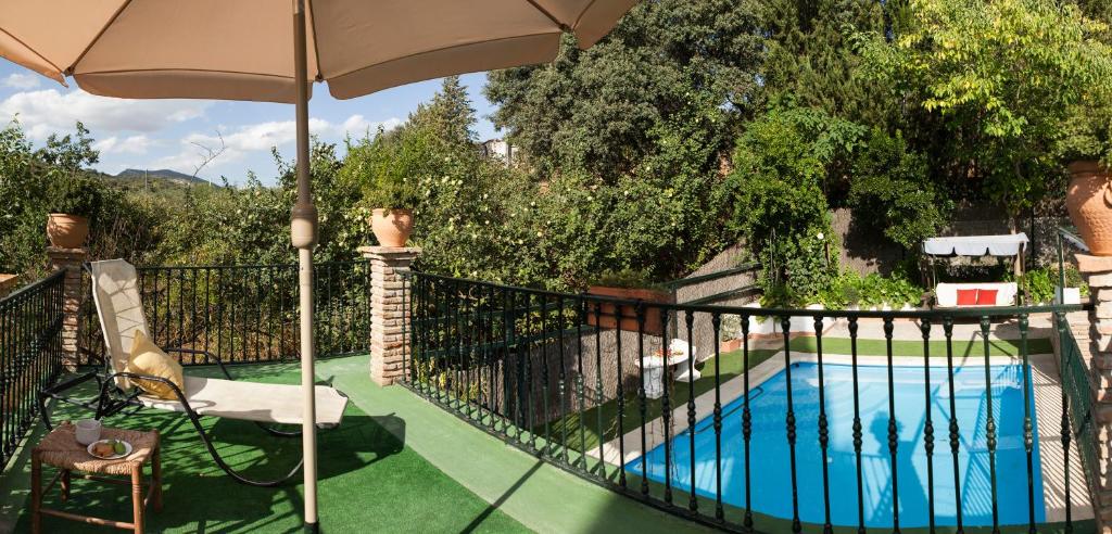 a balcony with an umbrella and a swimming pool at Cortijo La Algallumbilla in Carcabuey