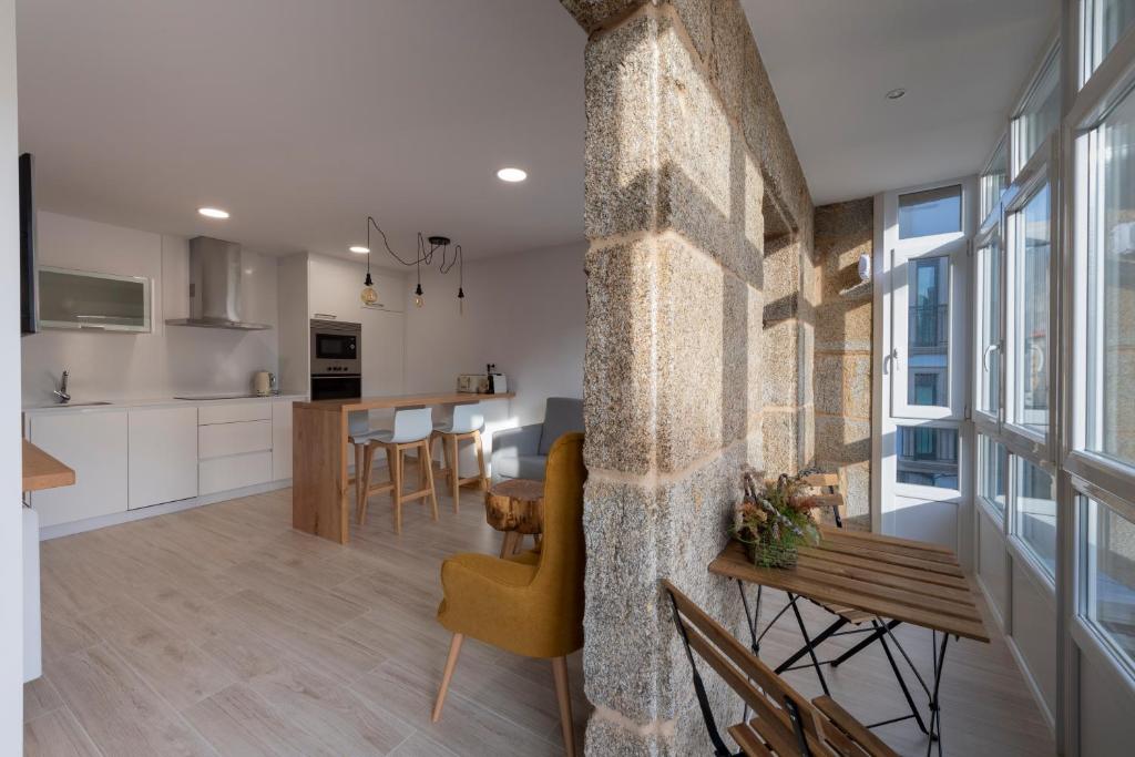 cocina y sala de estar con pared de piedra en Apartamentos Mar de Fondo Muxia, en Muxía