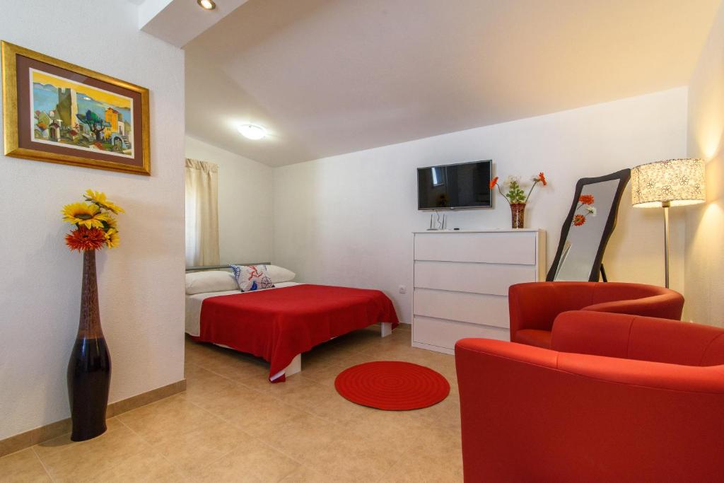 uma sala de estar com uma cadeira vermelha e uma cama em Apartments Beba - peaceful location em Trogir