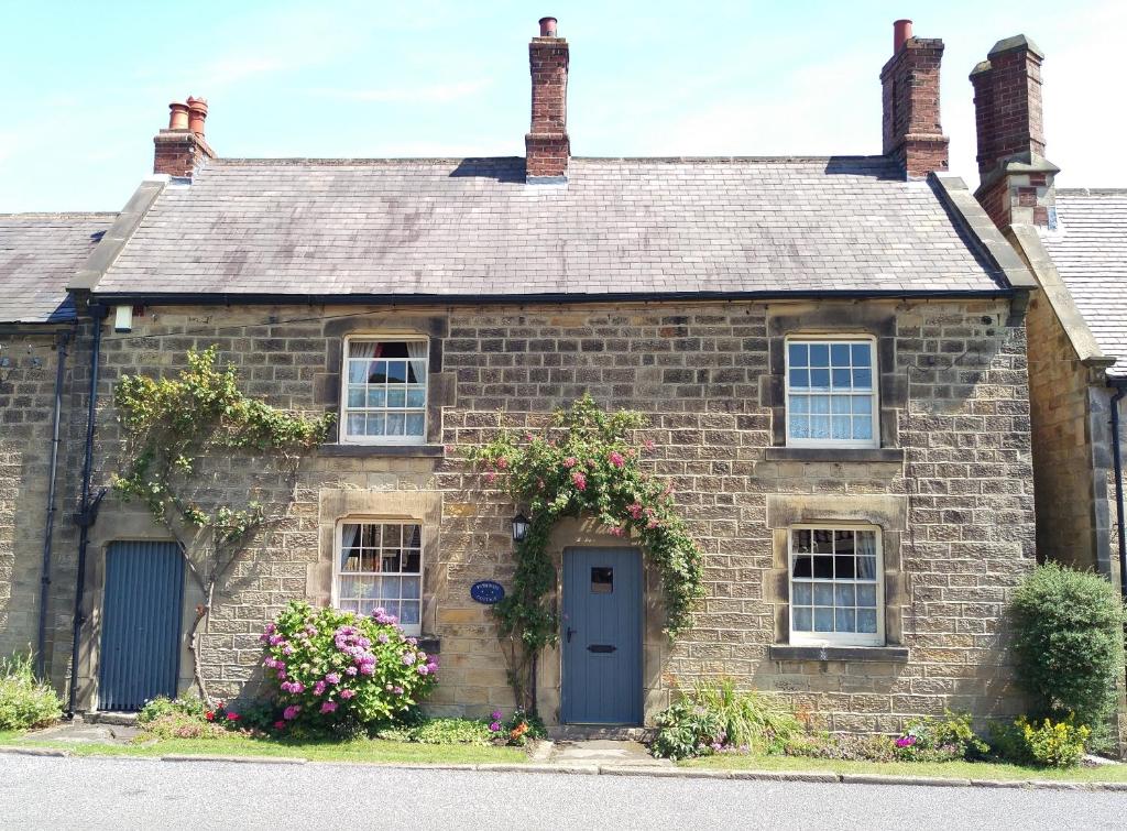 an old brick house with flowers in front of it at Pathways Cottage in Higham