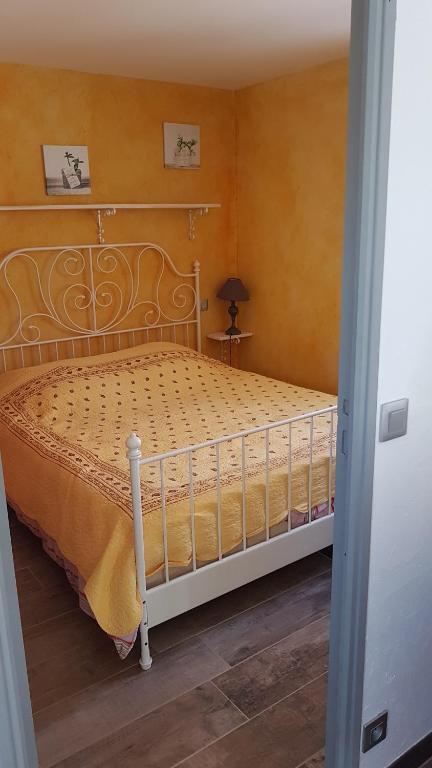 um quarto com uma cama branca e um cobertor amarelo em 1262 Chemin des Pignatelles em La Motte