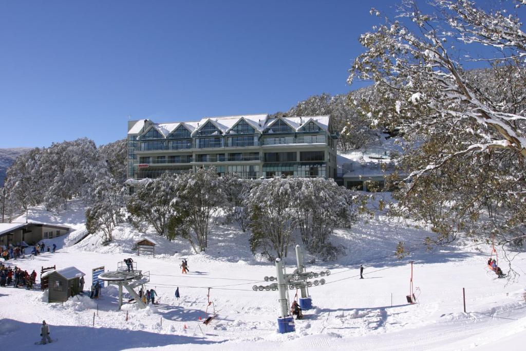 a snow covered ski slope with a large building at Falls Creek Country Club in Falls Creek