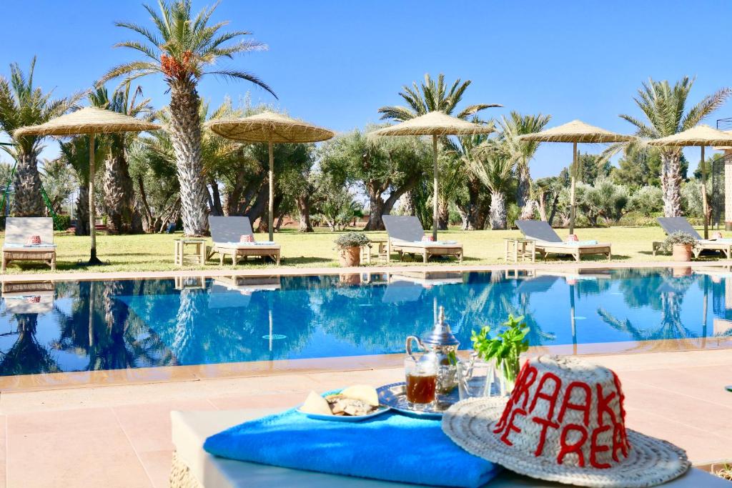 uma mesa com comida e bebidas junto a uma piscina em Marrakech Retreat By La Siredrah em Marrakech