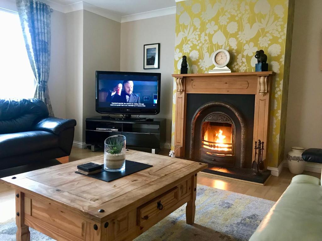 ein Wohnzimmer mit Kamin und Fernseher in der Unterkunft Causeway Holiday Homes in Coleraine