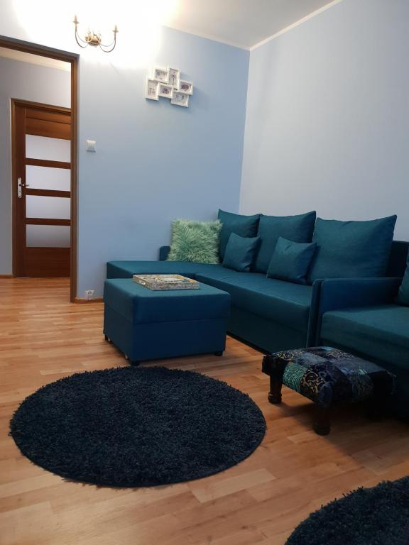 ein Wohnzimmer mit einem blauen Sofa und einem Teppich in der Unterkunft Apartament Wyszynskiego in Białystok