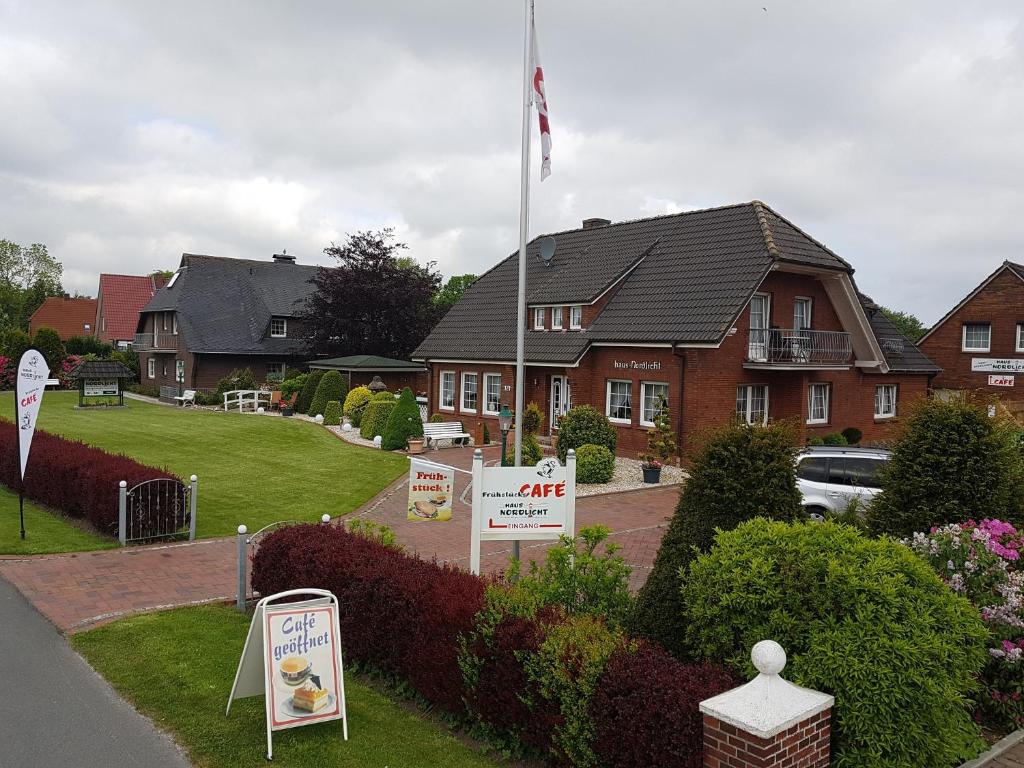 une maison avec un drapeau et des panneaux devant elle dans l'établissement Hausnordlicht FEWO 1, à Dornum