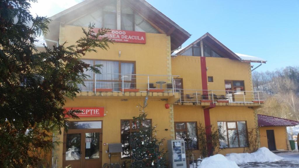 un edificio amarillo con un cartel. en Complex Dracula & Spa, en Căpăţîneni-Ungureni