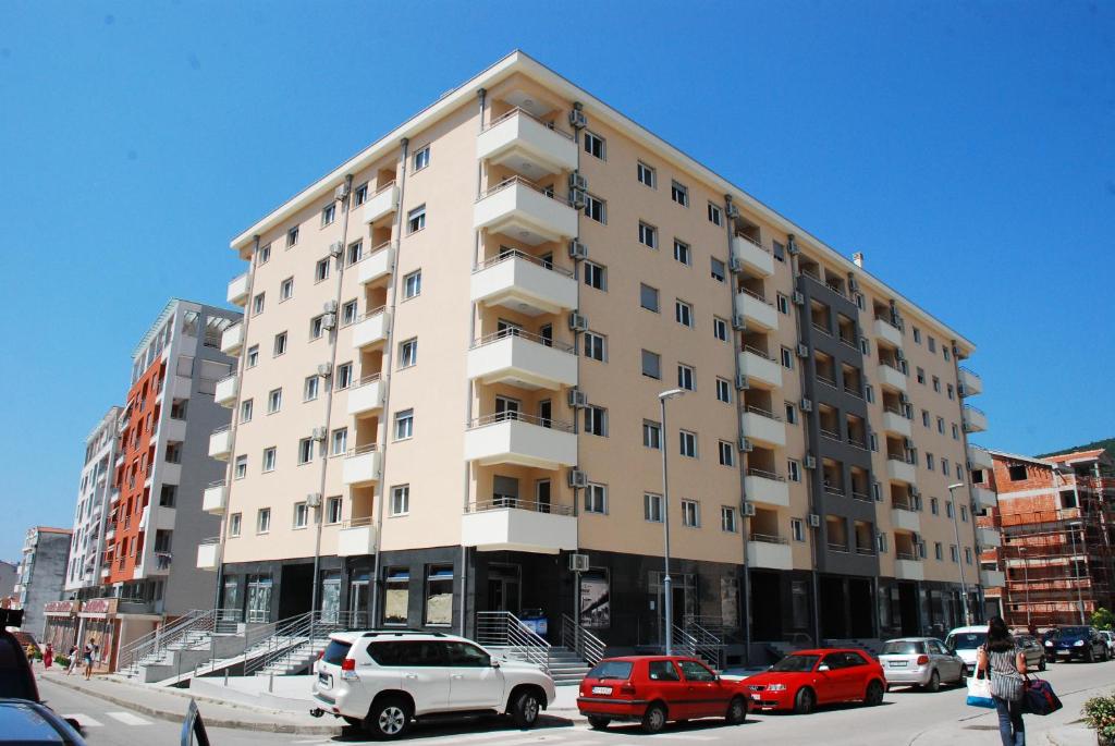 a large white building with cars parked in a parking lot at Budva Garden Apartments in Budva