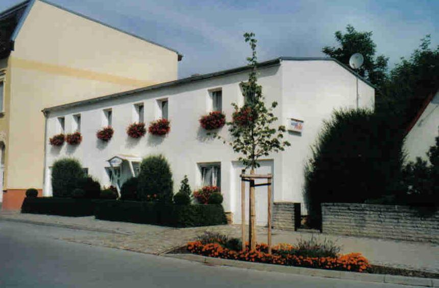 a white building with flowers in front of it at Pension Heike in Schönebeck