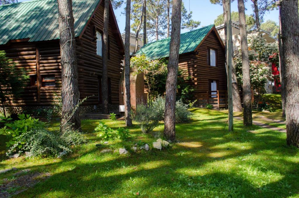 a log cabin with a green roof and trees at Cabañas y Apart Utopia in Mar de las Pampas