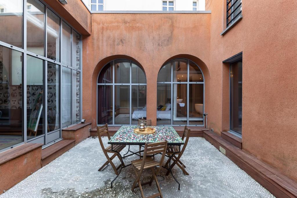 a table and chairs on a patio with windows at LE RIAD - Loft de 230 m2 au cœur de Nantes in Nantes