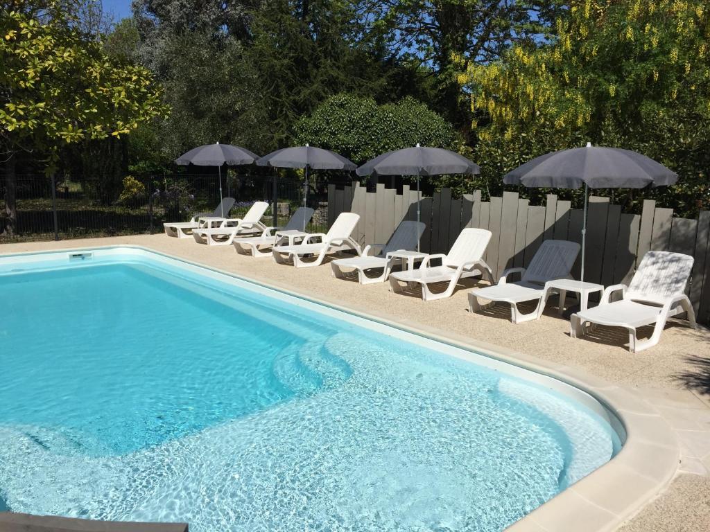 une piscine avec chaises longues et parasols dans l'établissement Les Suites de l'Alvertonne, à Arvert