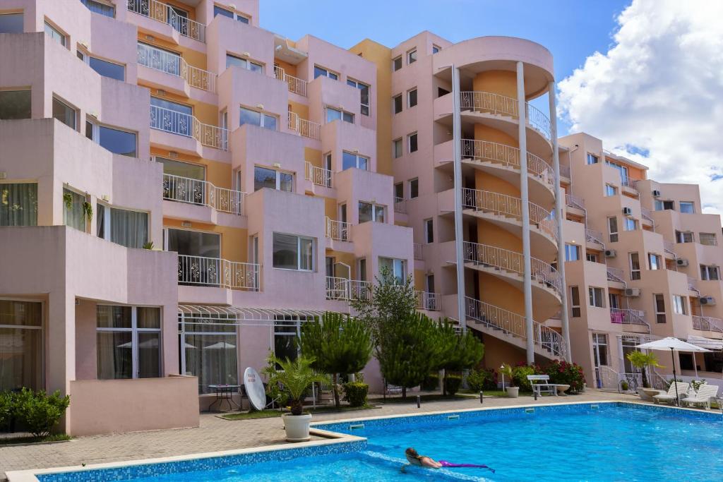 a person swimming in a pool in front of a building at Vanilla Garden Apartments in Sunny Beach