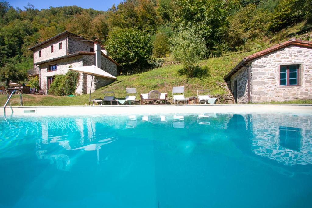 una piscina con sillas y una casa en Holiday villa with pool, Mulino del Pita en Barga