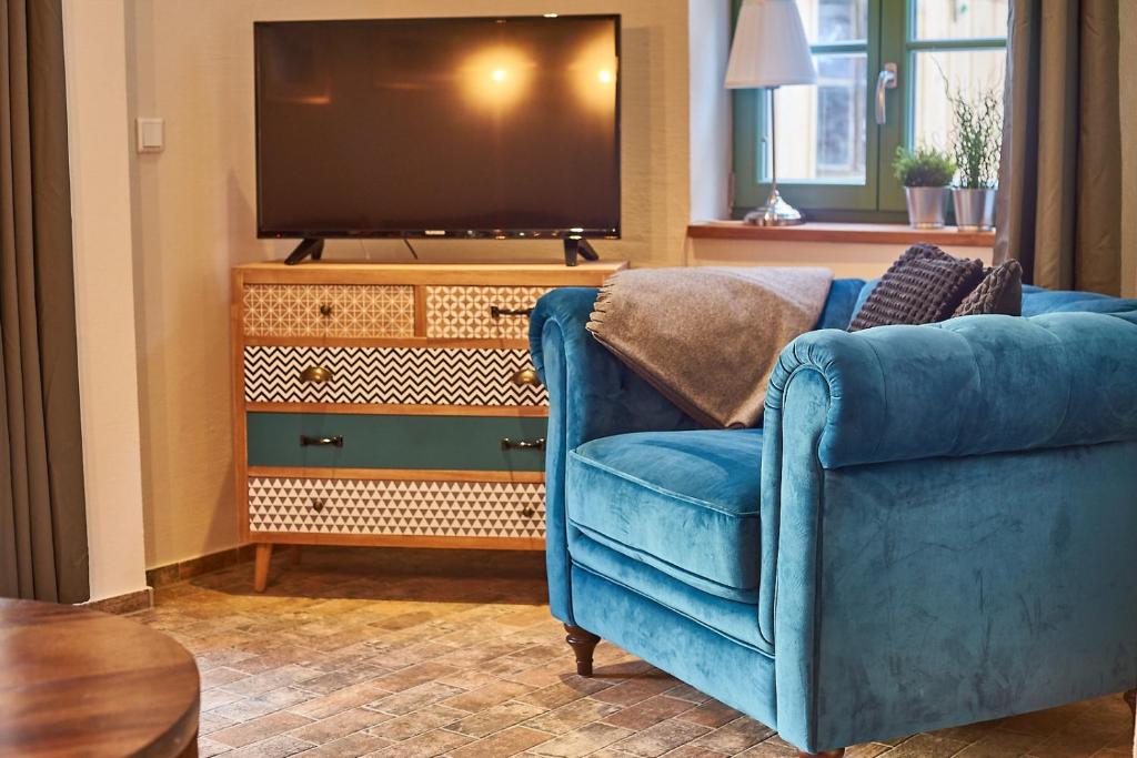 a living room with a blue chair and a television at Apartmenthaus Seiler in Quedlinburg