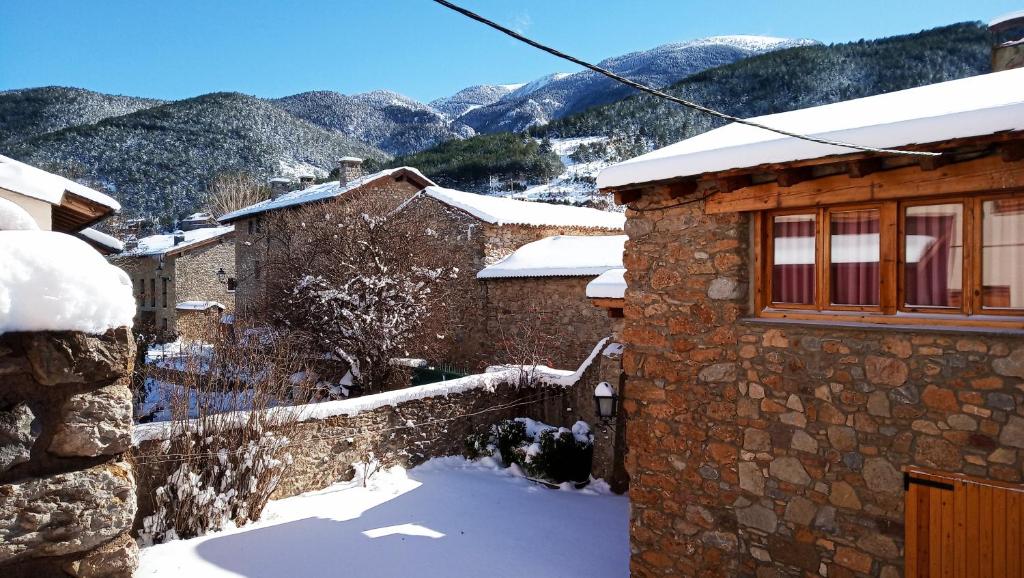 une maison dans la neige avec des montagnes en arrière-plan dans l'établissement El Paller d'Urús, à Urus