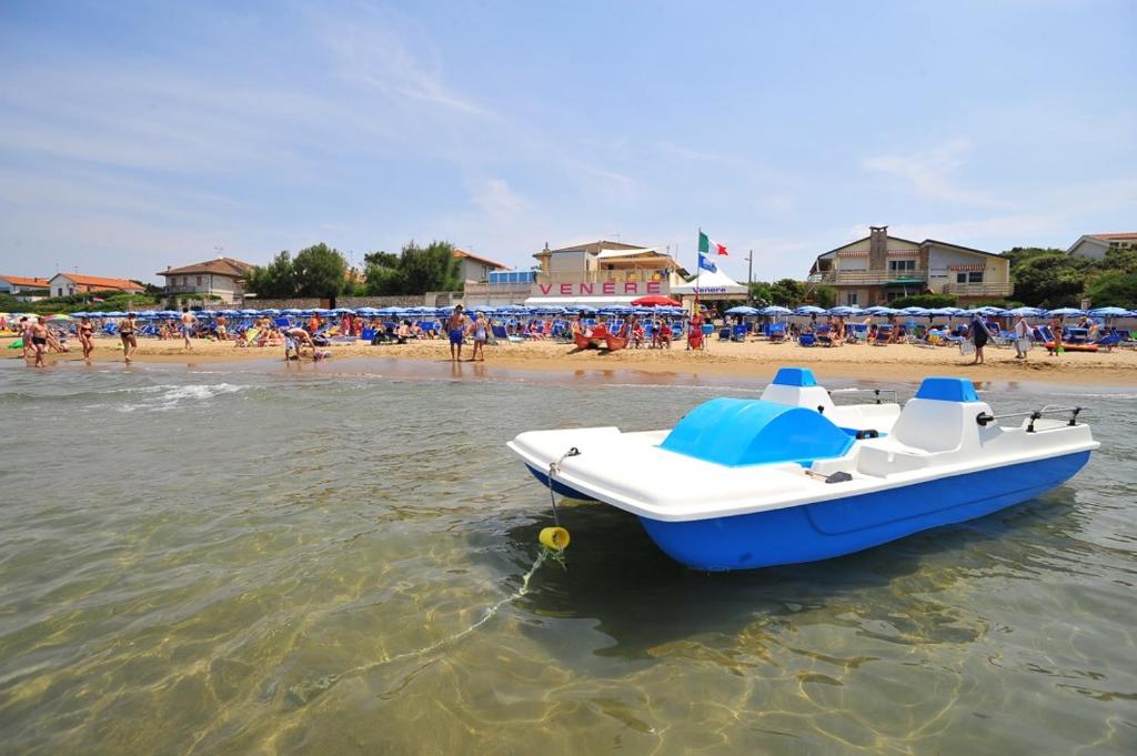 un barco azul y blanco en el agua en una playa en Appartamenti Venere, en San Vincenzo
