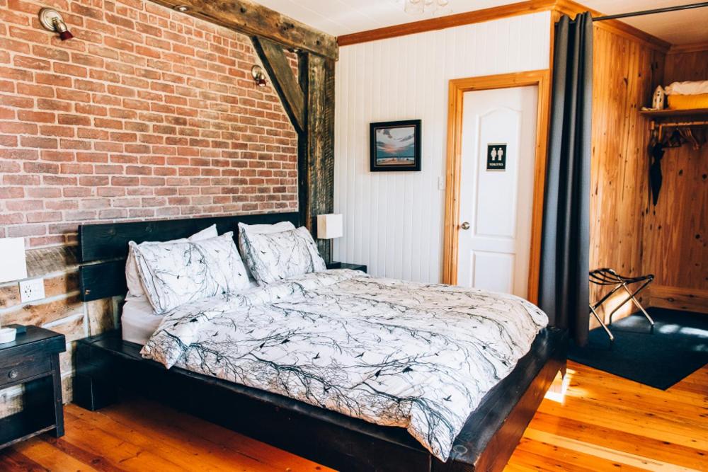a bedroom with a bed and a brick wall at Gîte TerreCiel in Baie-Saint-Paul