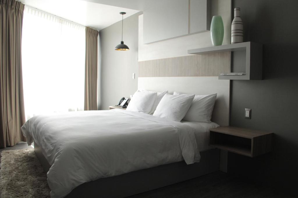 - une chambre avec un grand lit blanc et une fenêtre dans l'établissement ESDUMA HK HOTEL Pachuca, à Pachuca