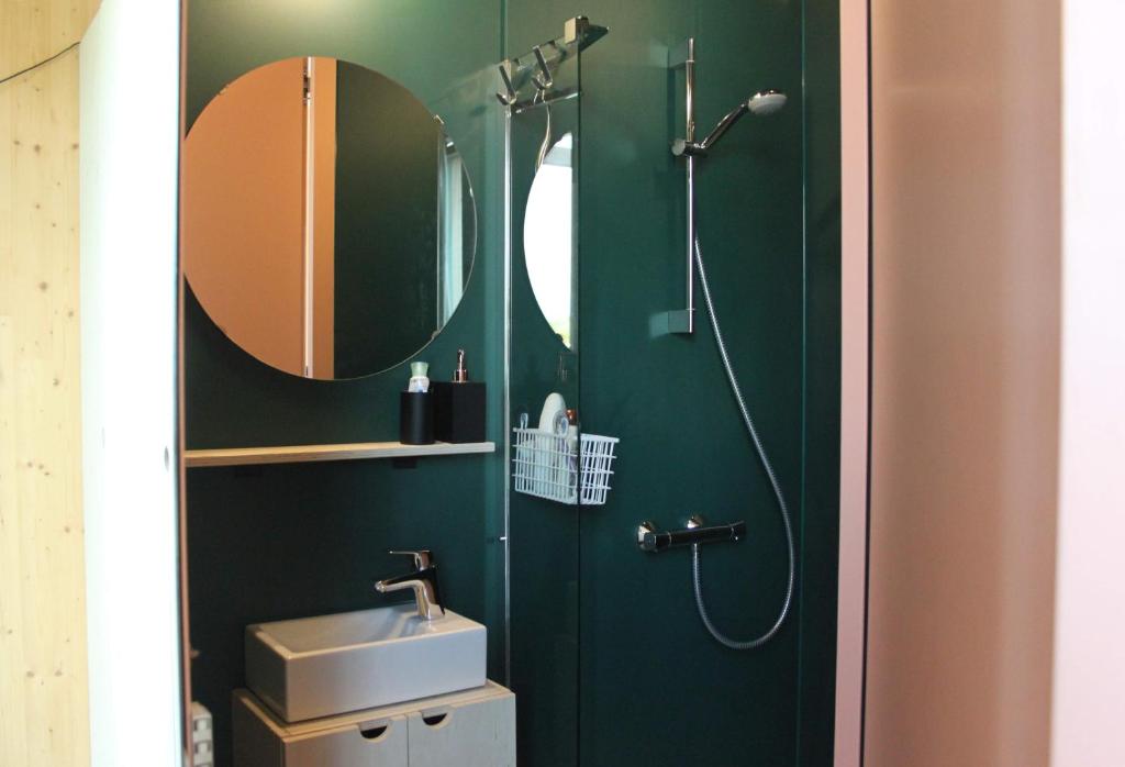 a green bathroom with a shower and a sink at ROOTS Tiny House in Tilburg