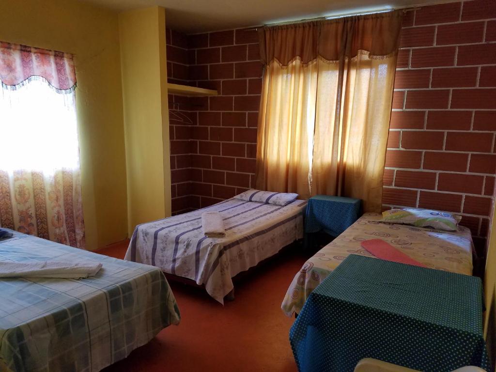 um quarto com duas camas e uma parede de tijolos em Casa de Alexis em Puerto Baquerizo Moreno