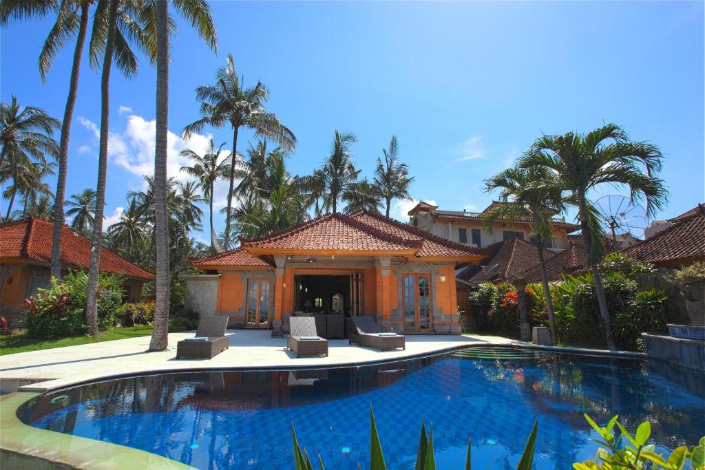 - une piscine en face d'une maison avec des palmiers dans l'établissement Villa Rama, à Candidasa