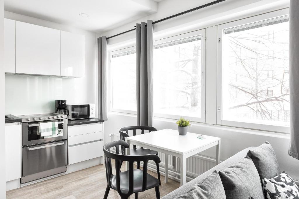 Hiisi Homes Helsinki Haaga في هلسنكي: مطبخ وغرفة معيشة مع طاولة وكراسي