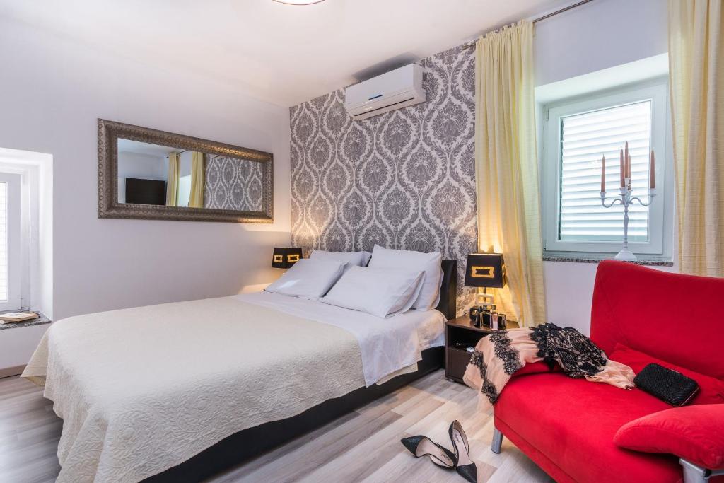 1 dormitorio con 1 cama y 1 silla roja en Apartments Marina en Zadar