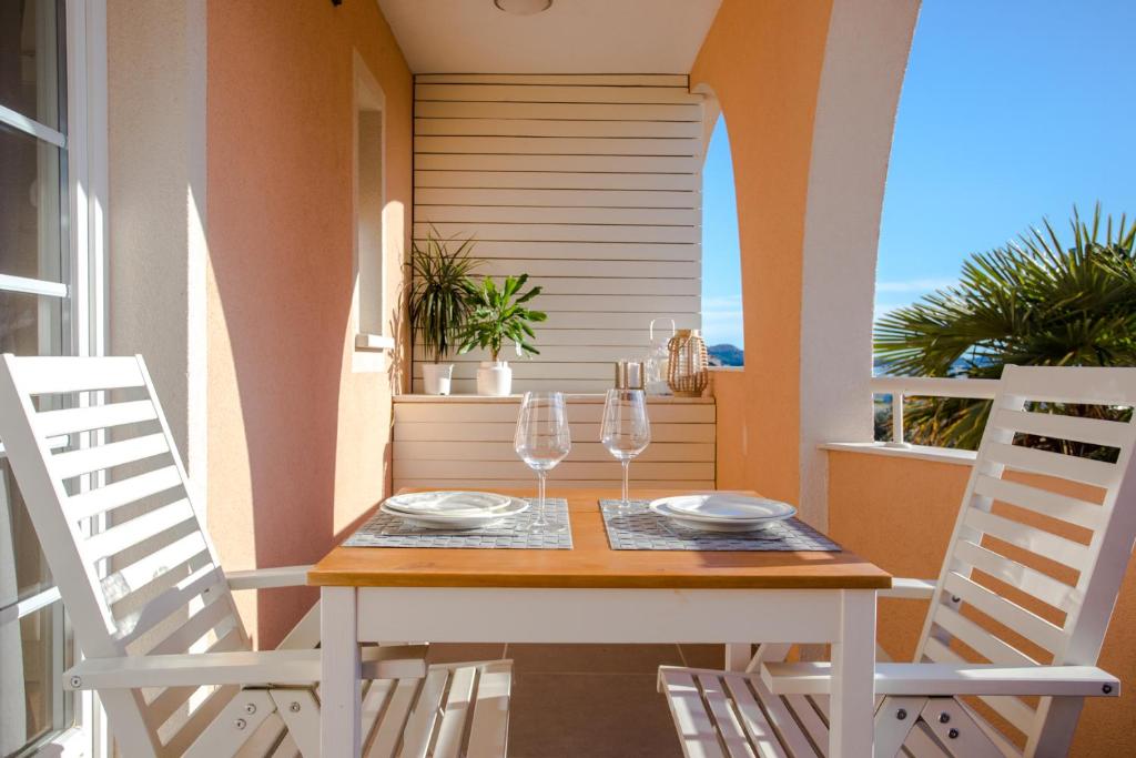 een tafel met 2 stoelen en wijnglazen op een balkon bij Villa Lena in Pakoštane