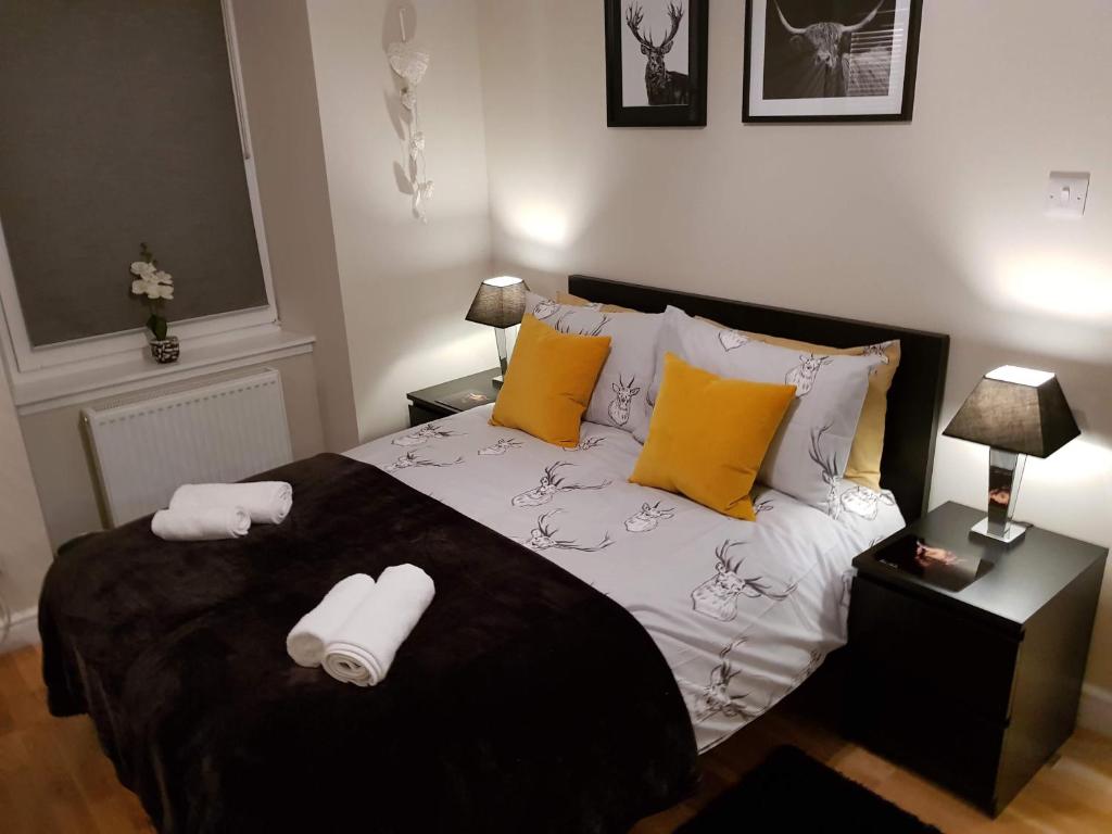 um quarto com uma cama preta e branca com almofadas amarelas em Smart & Cozy Holiday Apartment in the city centre em Inverness