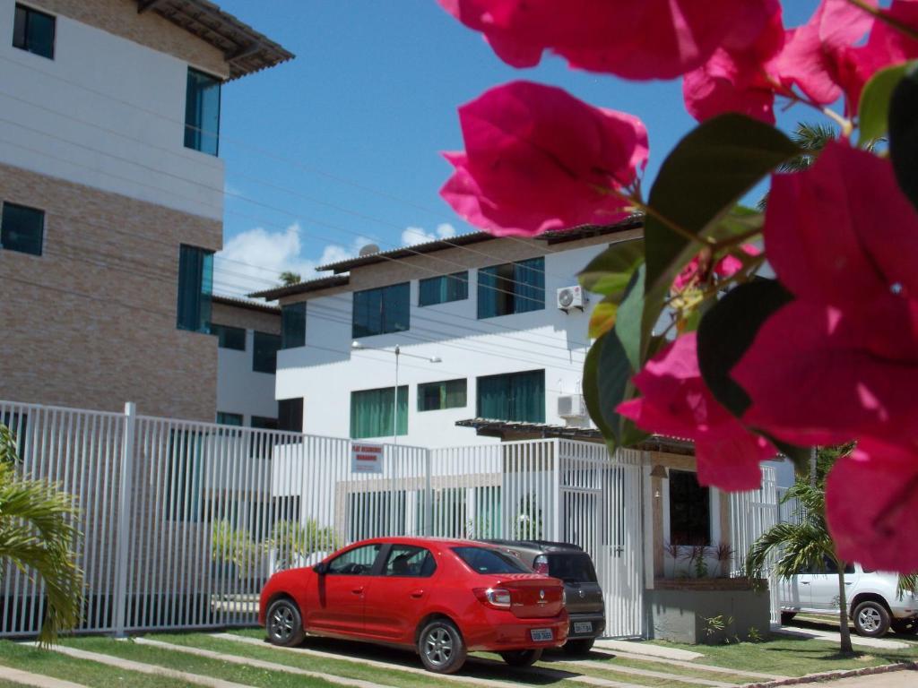 un coche rojo estacionado frente a una valla blanca en Apartamento lindo e completo, de frente para o mar, en Maragogi