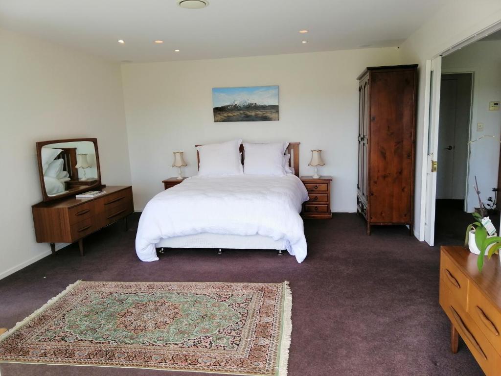 a bedroom with a large white bed and a mirror at Shurinji in Whanganui