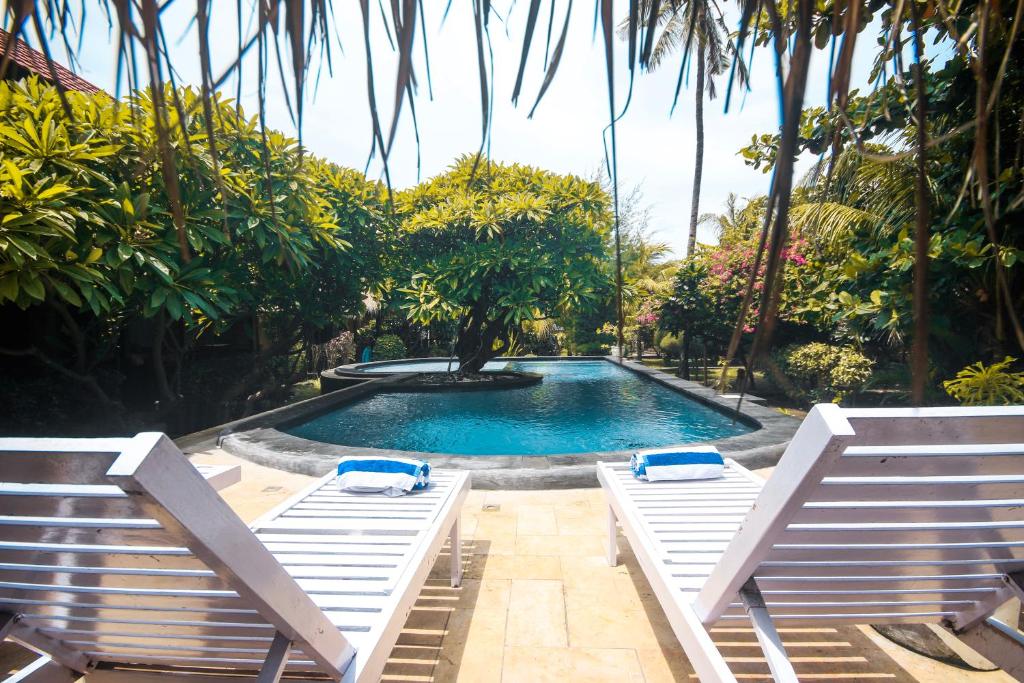 a swimming pool with two lounge chairs next to it at Sejuk Cottages in Gili Air