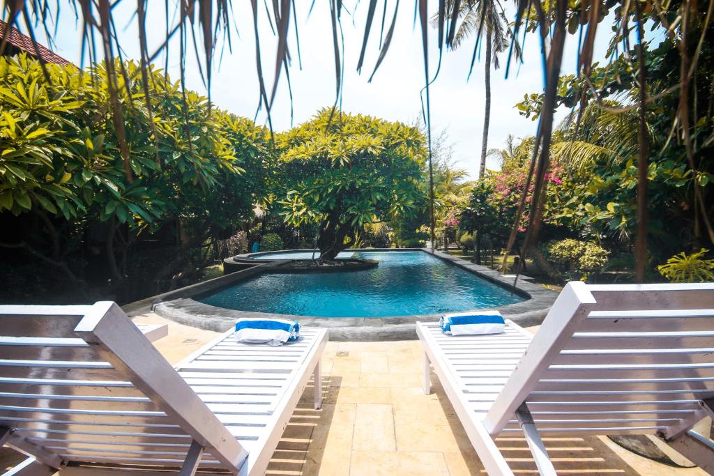 una piscina con due sedie a sdraio accanto di Sejuk Cottages a Gili Air