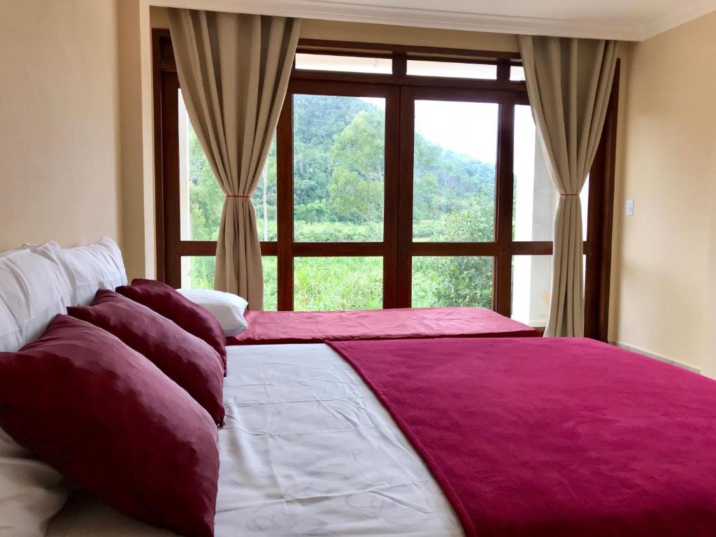 ein Schlafzimmer mit einem großen Bett und einem großen Fenster in der Unterkunft Ecopousada Garten Haus in Santa Teresa