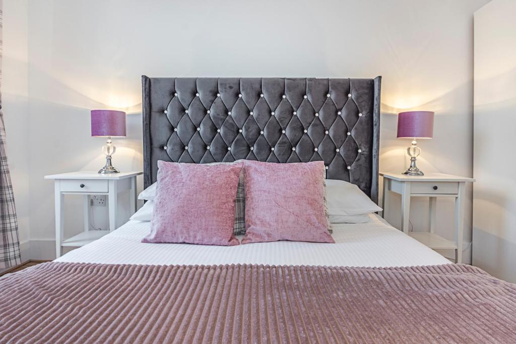 - une chambre avec un lit avec des oreillers roses et 2 tables dans l'établissement Knightsbridge Dream Apartment, à Londres