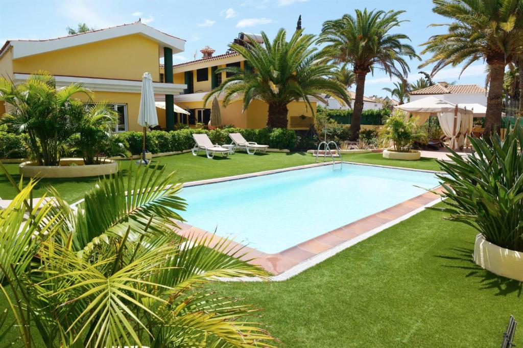 una piscina frente a una casa con palmeras en Villa Maspalomas Golf Court, en Maspalomas