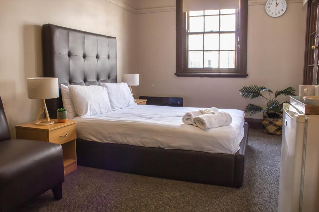 a bedroom with a large bed with towels on it at Campsie Hotel in Sydney