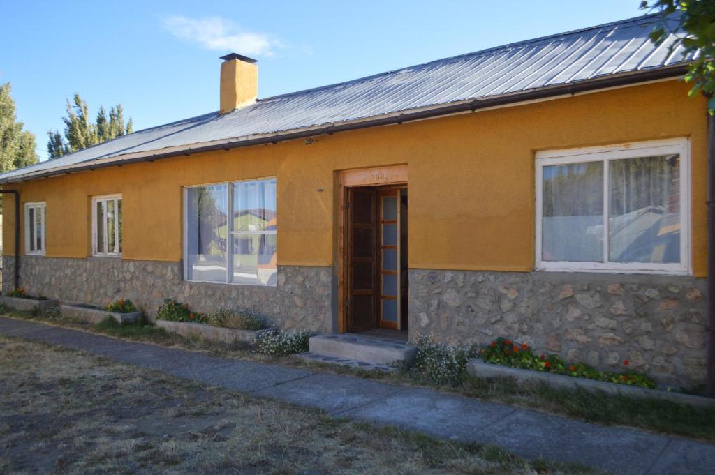 a yellow house with a door and windows at Hostal y Cabañas Vientos del Sur in Puerto Ingeniero Ibáñez