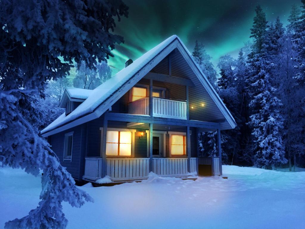 a cabin in the snow with the northern lights at Villa Aurela in Rovaniemi