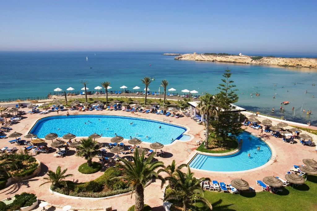 an overhead view of a swimming pool with umbrellas and the ocean at Regency Hotel & Spa in Monastir