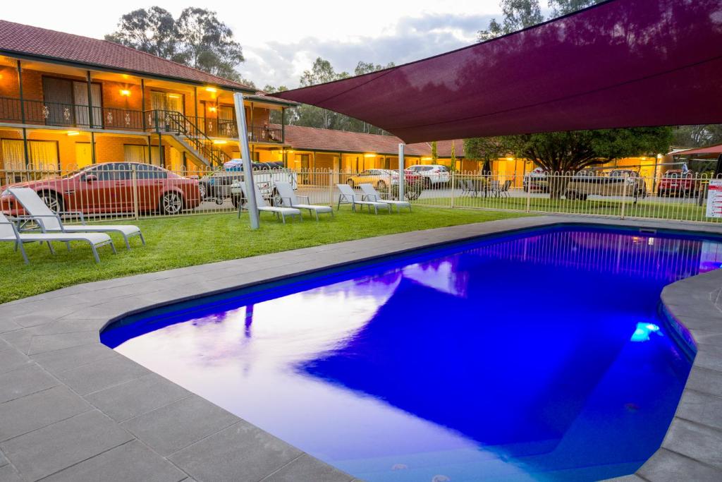 une piscine bleue en face d'un bâtiment dans l'établissement Advance Motel, à Wangaratta