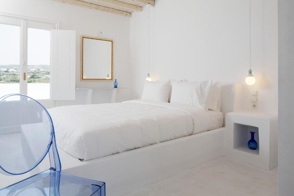 a white bedroom with a bed and a glass table at Aether Boutique Stay in Glastros