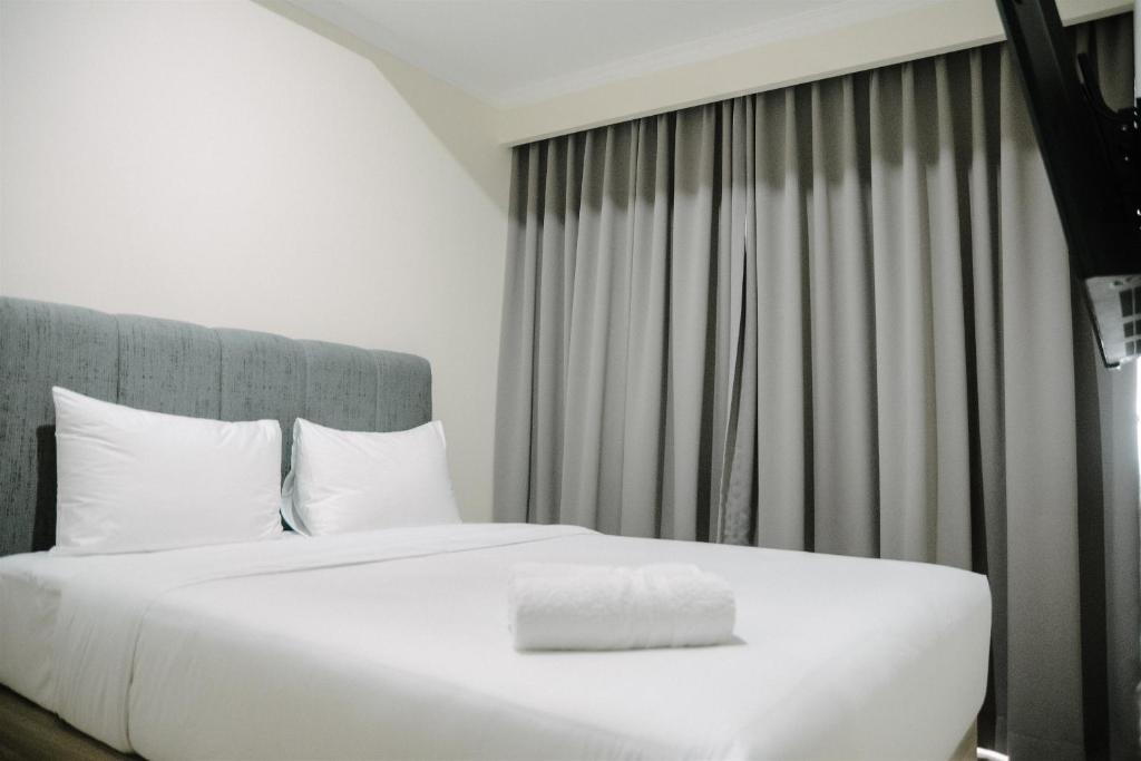 Un dormitorio con una gran cama blanca y una ventana. en 2BR Deluxe and Modern Menteng Park Apartment By Travelio, en Yakarta