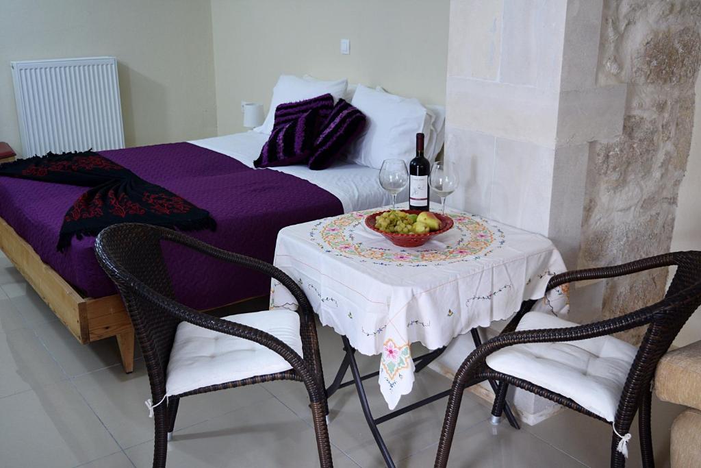 - une table avec une bouteille de vin et 2 chaises dans l'établissement Arches Eleftherna, à Elefterna