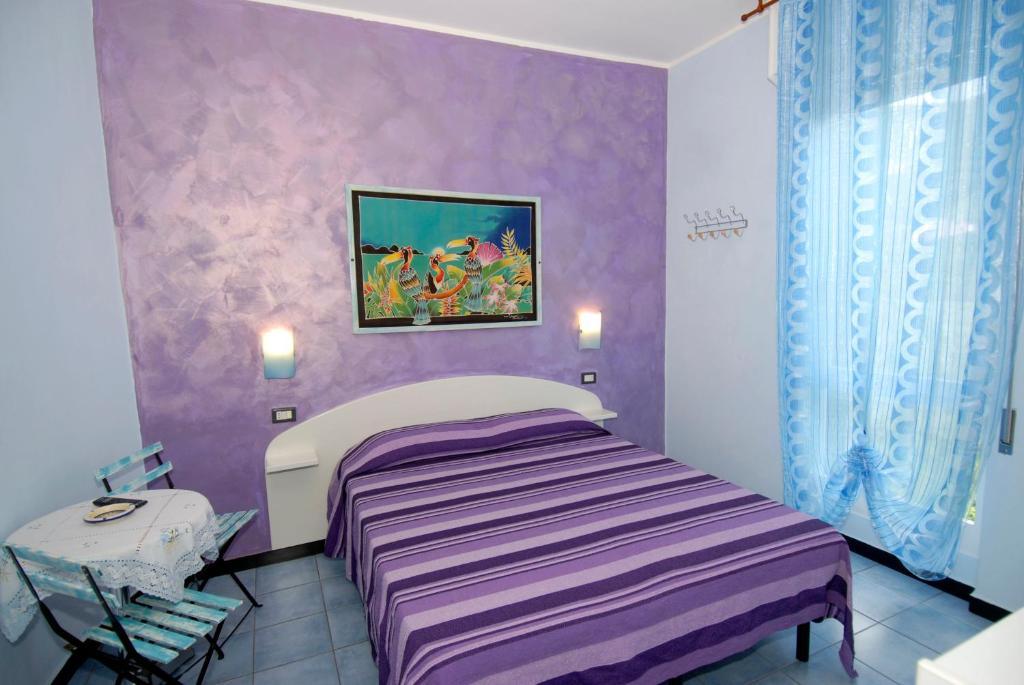 1 dormitorio con cama y pared púrpura en Villa Caribe affittacamere, en Monterosso al Mare