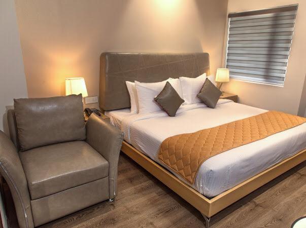 um quarto com uma cama e uma cadeira em The Mayberry -A Bergamont Group of Hotels em Tiruppūr
