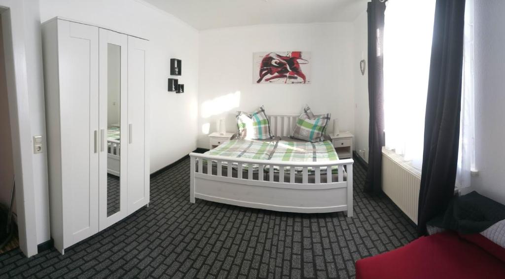 Dormitorio pequeño con cama blanca y espejo en Ferienwohnung Charlett, en Dresden