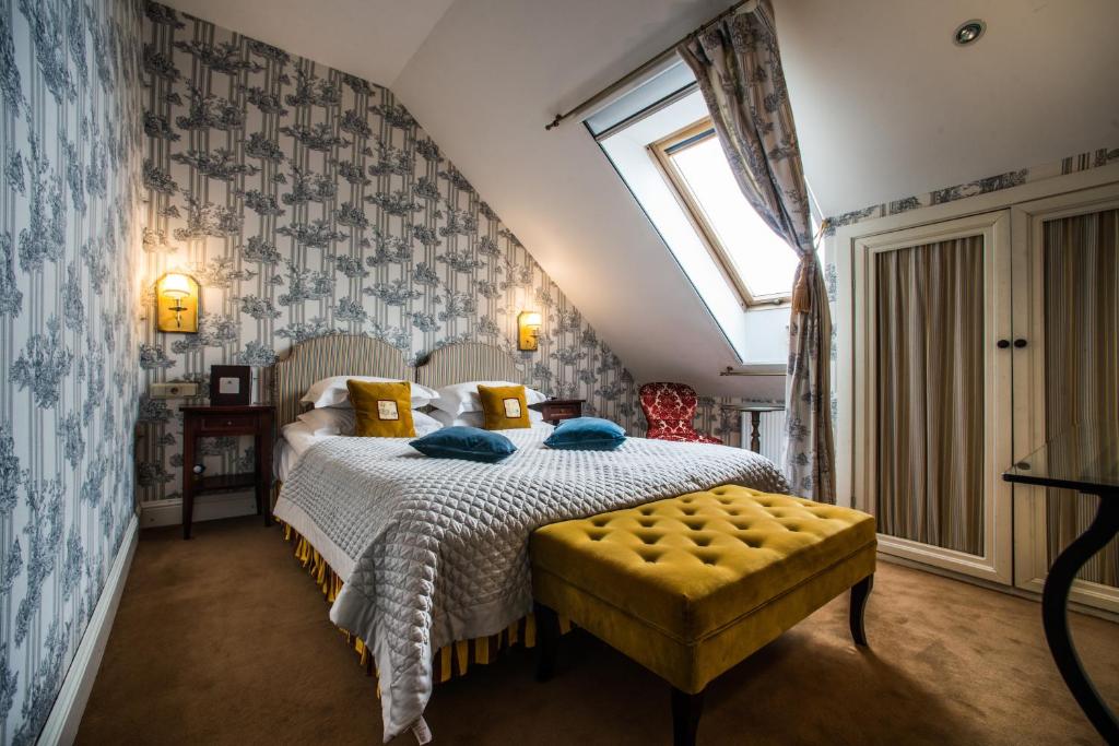 a bedroom with a bed with a yellow ottoman and a window at Apvalaus stalo klubas in Trakai