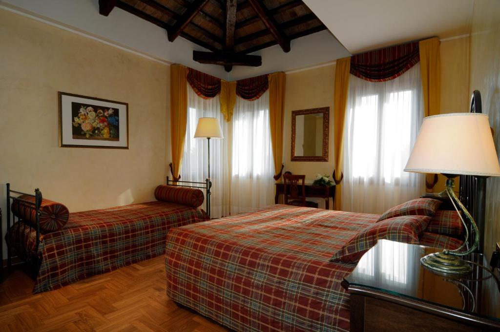 a bedroom with two beds and a lamp and curtains at Villa Goetzen in Dolo